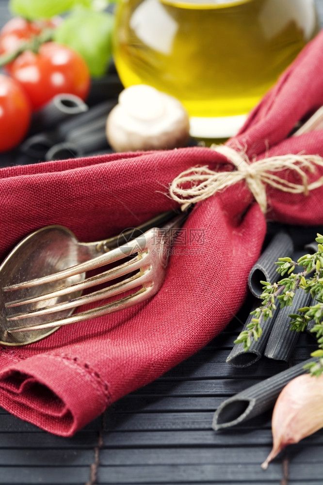 勺子叉餐巾和意大利面成分粉橄榄油巴西尔蘑菇番茄柠檬图片
