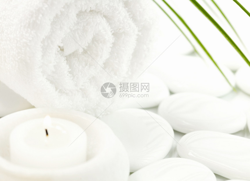 白石子蜡烛毛巾和棕榈叶在白上有选择的焦点图片