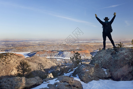 快乐的男徒步者站在岩石上仰望着马牙储藏室柯林斯堡镇和科罗拉多平原图片