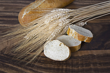 黑胡桃板上有小麦的新鲜面包图片