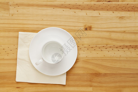 松木桌上的白瓷咖啡杯和餐巾顶视图图片