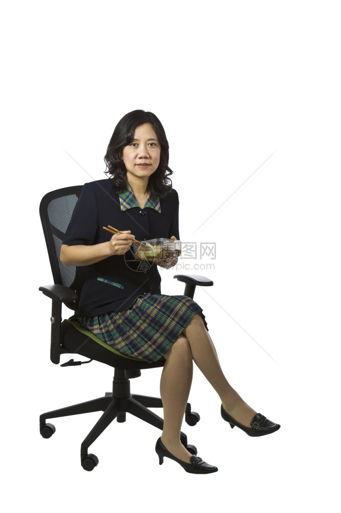 亚裔身穿商业因果服装的妇女在白种背景坐椅子上时吃午餐图片