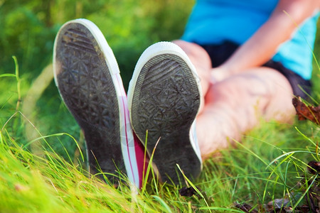 阳光明媚的夏日穿着粉色运动鞋在草地上穿着女孩腿的粉色运动鞋图片