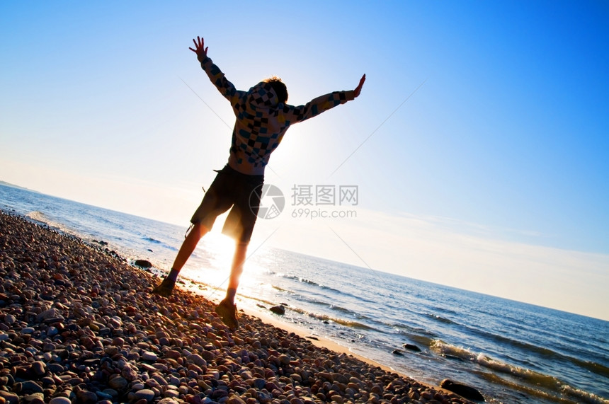 快乐的男孩在海滩上欢快的跳跃图片