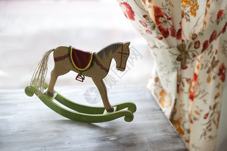 马玩具在古老背景上带有窗帘的马玩具图片