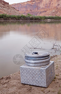 绿河岸色小型金属便携式厕所在犹他州Canyonland河上旅行所需设备背景图片