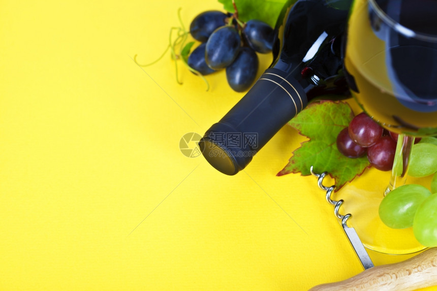 黄色背景的红酒和新鲜葡萄图片