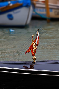 在威尼斯主要运河意大利的黑色高多拉上的金雕像图片