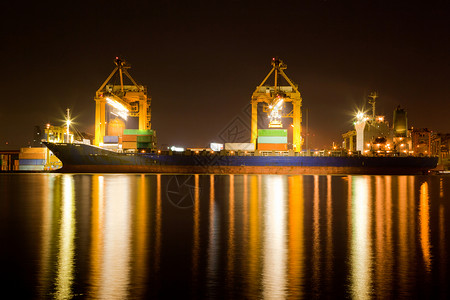 装水的容器夜间在曼谷造船站码头卸载和装货物的工业船舶具有作起重桥的机用于物流进口背景背景