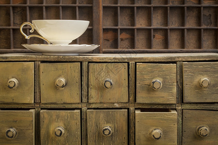 古典茶杯在生锈的药用抽屉柜子上图片