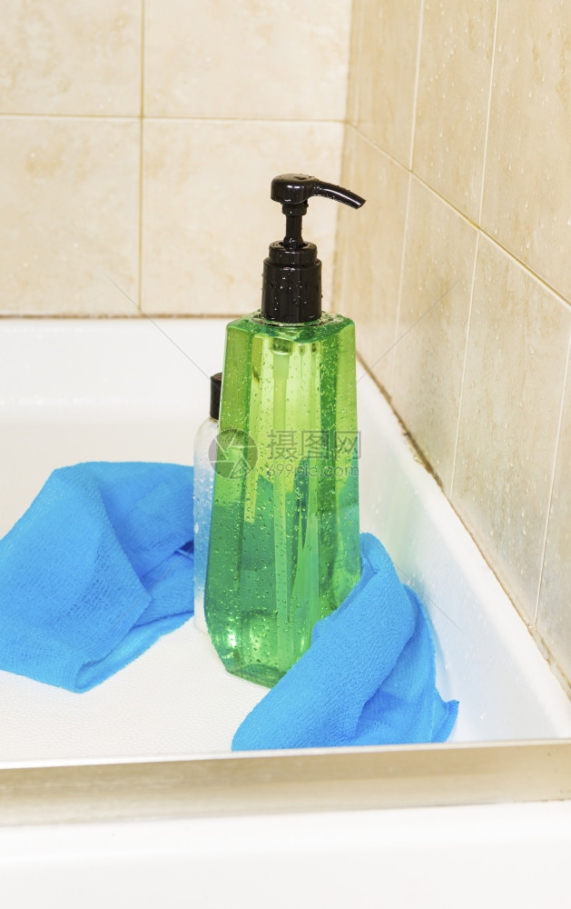 高绿色淋浴胶瓶垂直照片配有水滴洗衣布和一小瓶发机底有淋浴摊图片