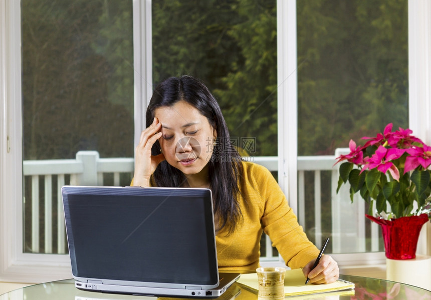 在家工作看重压力用笔记本电脑在玻璃桌上用笔记本电脑有大窗户背景的亚洲成熟妇女图片