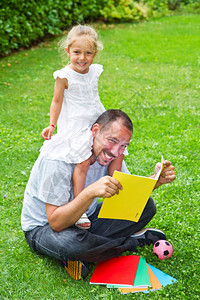 在花园的草地上父亲念书给女儿图片