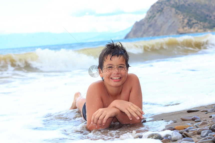 快乐笑的男孩十二岁在海边的图片