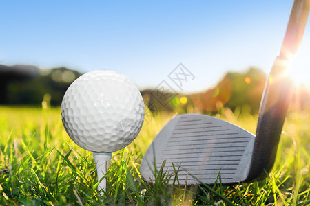 高尔夫球在白茶和高尔夫俱乐部上准备绿色草高尔夫球场蓝阳光的天空图片