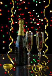 一瓶香槟的垂直照片两杯高的优雅眼镜上面有黄丝带和背景灯光图片