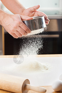 人手用把面粉擦透用来烘烤的筛子图片