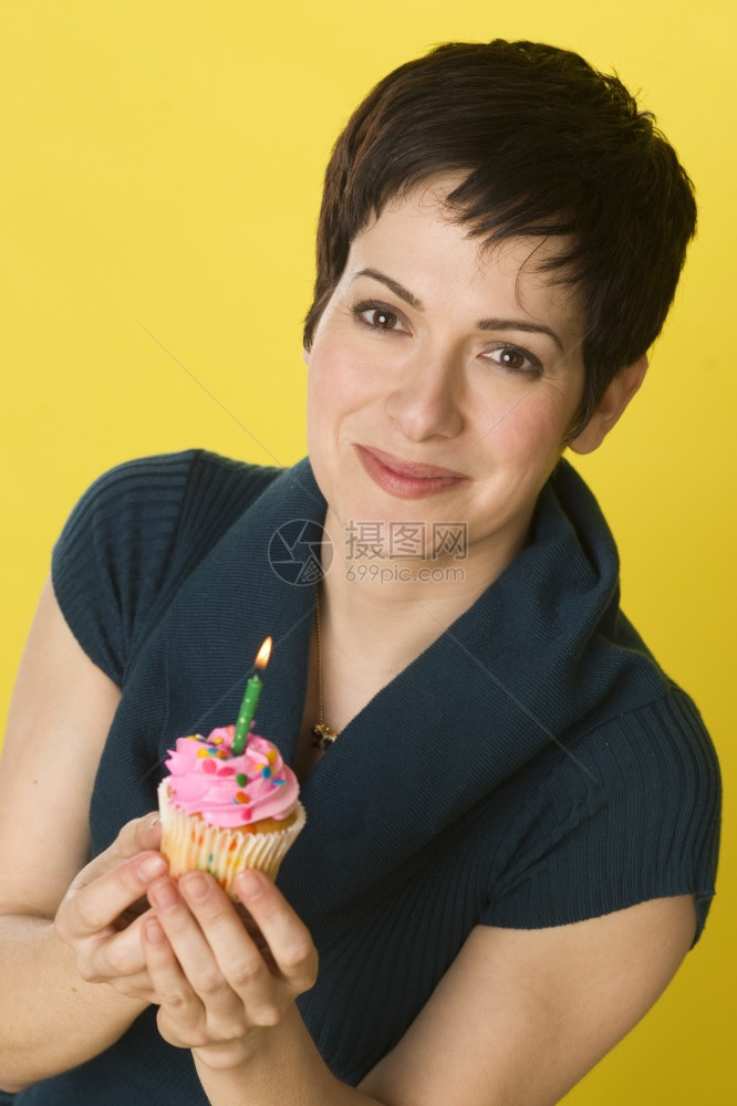 快乐的女子坚持出杯蛋糕一个蜡烛庆祝生日图片
