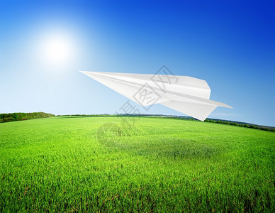 折纸飞机在绿色草上飞行的设计图图片