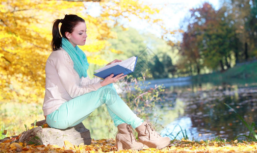 秋叶生活方式概念在秋季公园阅读书中临时女青年孩在休闲娱乐中放松图片