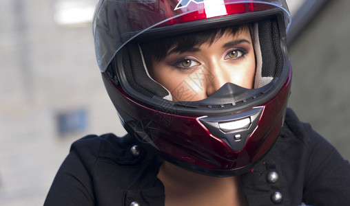 近距离的红色满脸的女孩头盔在摩托车上图片
