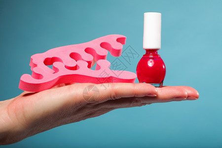 红指甲油和女手上的粉红色脚趾分离器图片