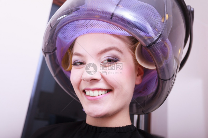美发容院的年轻女客户微笑着头发卷的姑娘发型师理吹风图片