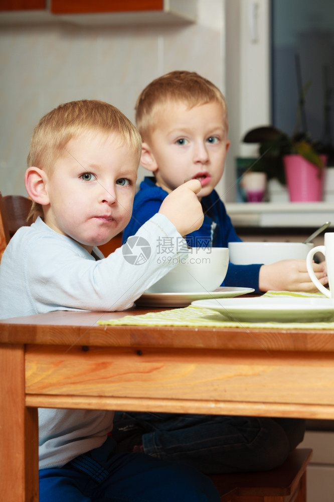 两个金发男孩子们在餐桌上吃玉米片早餐图片