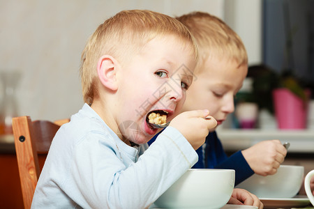 两个金发男孩子们在餐桌上吃玉米片早餐图片