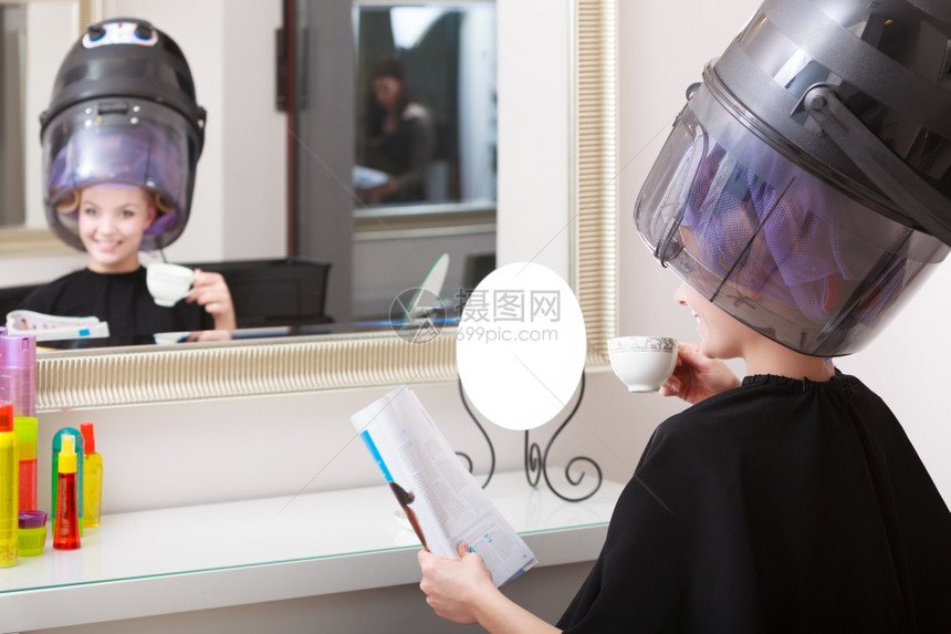 年轻女客户在美发容院阅读杂志图片