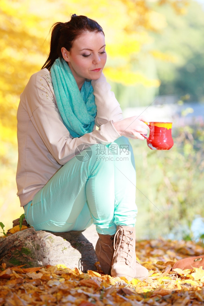 快乐的年轻女子在秋天公园享受热饮咖啡或茶图片