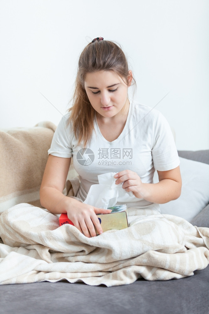 妇女坐在沙发上被毯子覆盖拉扯组织图片