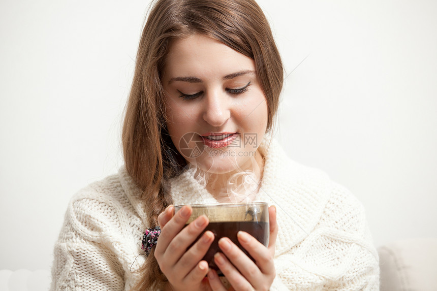 褐色女人的肖像看着蒸发的茶杯图片