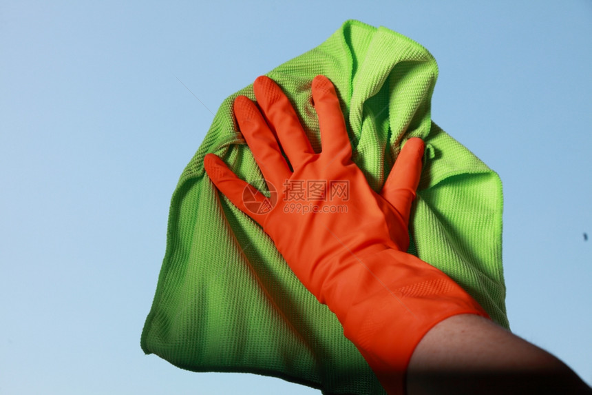用绿色抹布橙手套清洗窗户图片