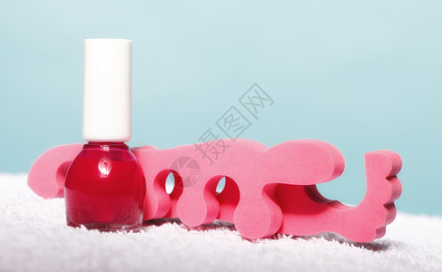红指甲油瓶和蓝底粉红色脚趾分离器图片