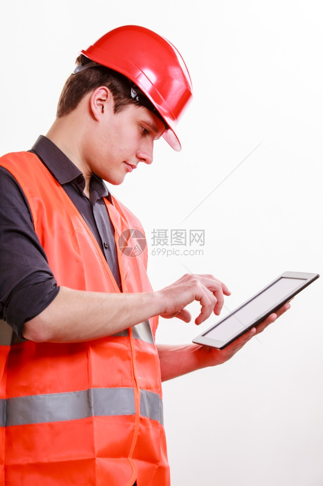 建筑工人年轻穿着橙色安全背心和红硬帽用白上孤立的平板触摸工业作技术室拍摄图片
