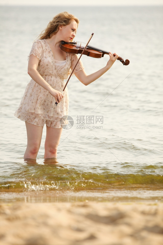 金发女孩在海滩上的音乐情人拿着小提琴喜欢音乐的概念图片