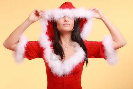 穿着圣达克拉斯服装蒙着眼睛的女士戴着圣诞帽子摘下黄色背景的帽子图片