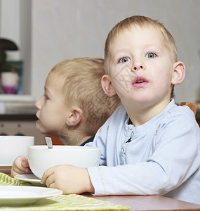 两位金发兄弟男孩子们在桌边吃玉米片早餐图片