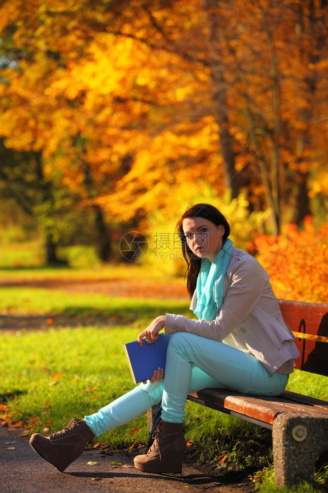 秋天的生活方式概念和谐自由偶然的年轻女孩在秋天公园和书一起坐在长椅上放松金色的叶子背景图片