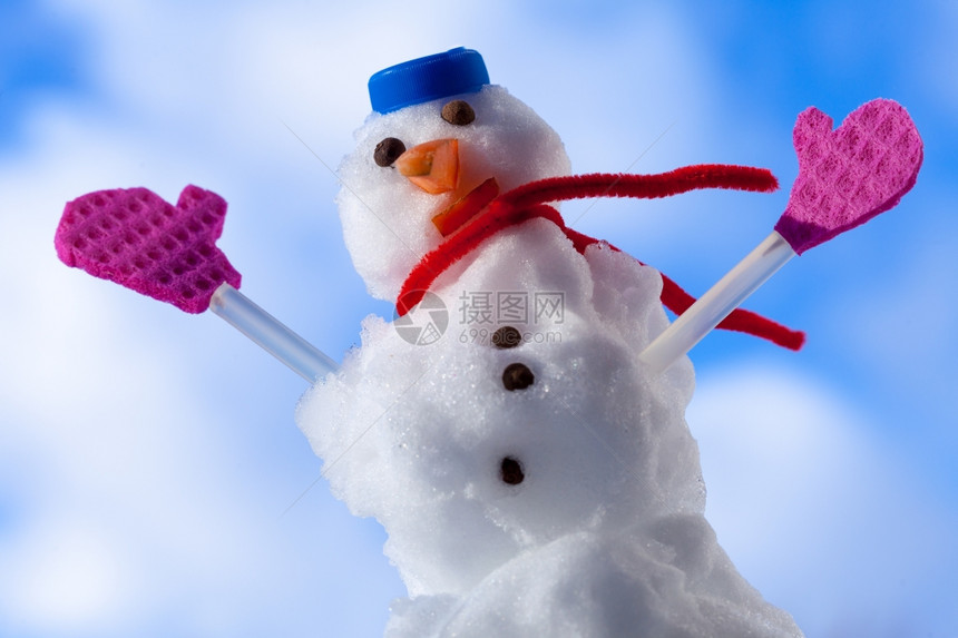 圣诞小雪人穿着蓝螺丝顶的色帽子红围巾和粉手套露天冬季节特别蓝天空背景图片