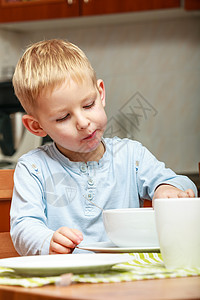 男孩在厨房桌边吃早饭图片