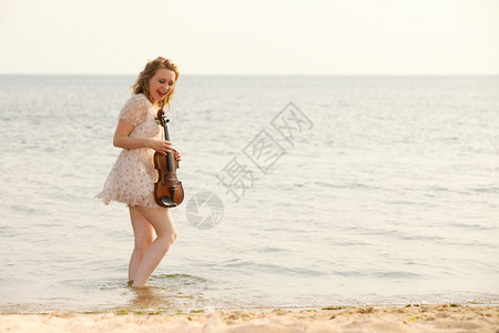 疯狂的金发女音乐情人在沙滩上玩小提琴喜欢音乐概念图片