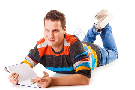躺在地板上阅读一本书的全年男学生为以白人背景孤立的考试做准备图片