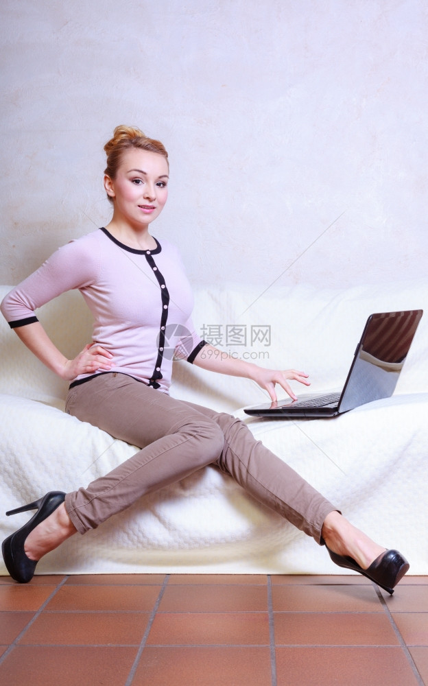 使用笔记本电脑坐在沙发上的年轻女商人或学生图片