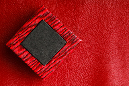皮革背景的红黑色矩形环首饰盒图片