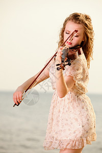 斯特拉迪瓦利乌斯海滩上玩小提琴的金发女孩音乐爱好者的概念背景