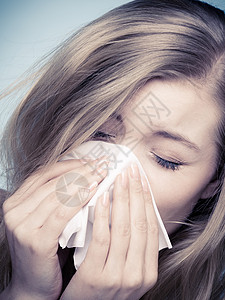 流感或过敏症状生病的年轻女孩在蓝色组织里打喷嚏保健工作室拍到图片