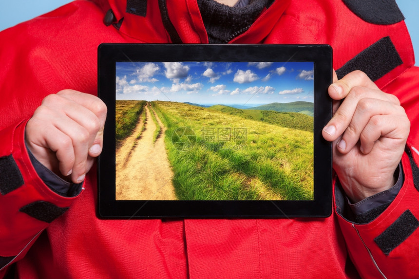 男手紧握着山地照片的木偶男人旅行者展示了屏幕平板电脑触摸梦想着冒险之旅技术和行图片