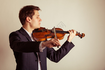 年轻优雅的小提琴家手在棕色古典音乐演播室拍小提琴背景图片